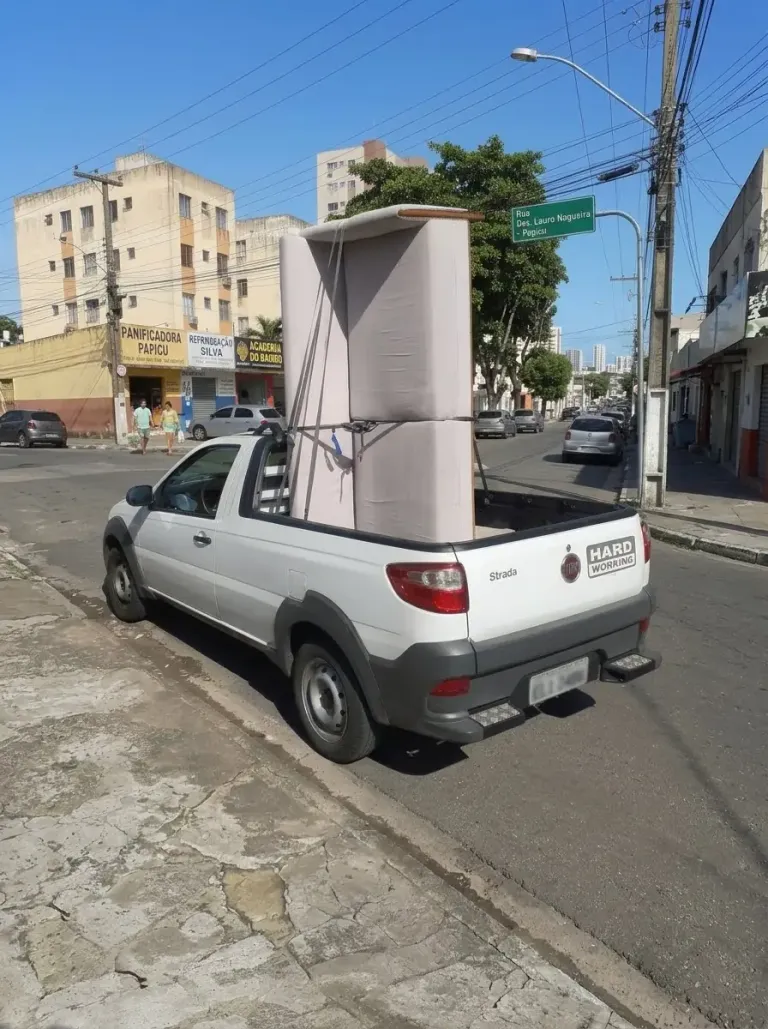 Sofá amarrado na caçamba de uma caminhonete branca, pronto para o carreto, em uma rua de Fortaleza